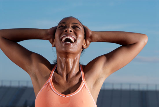 mujer joven y negra sudada por el ejercicio, sonriendo al cielo