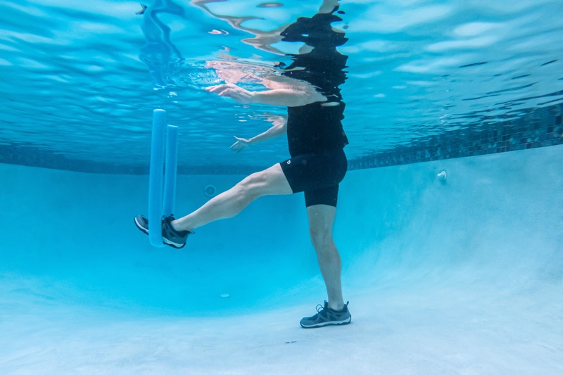 persona haciendo ejercicio en una piscina; foto tomada debajo del agua