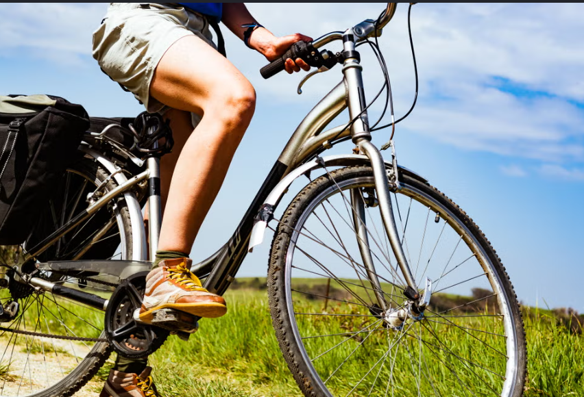 vista de un pie sobre un pedal de una bicicleta en una pradera